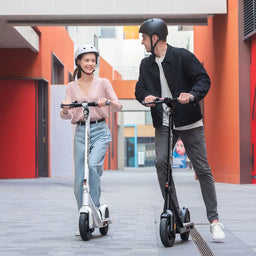 Two people riding electric scooters in an urban setting