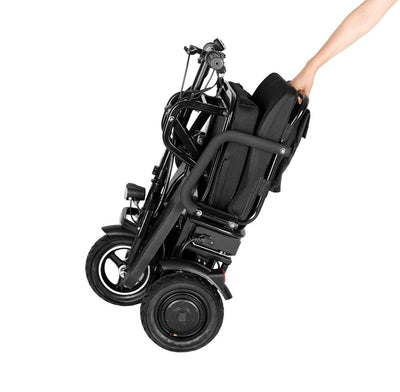 Black folding electric wheelchair being held by a person on a white background