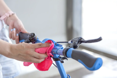 Person cleaning handlebar with microfibre cloth for electric scooter maintenance