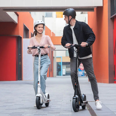 Two people riding electric scooters in an urban setting