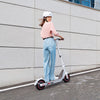 Person riding a scooter with a helmet on a city street.