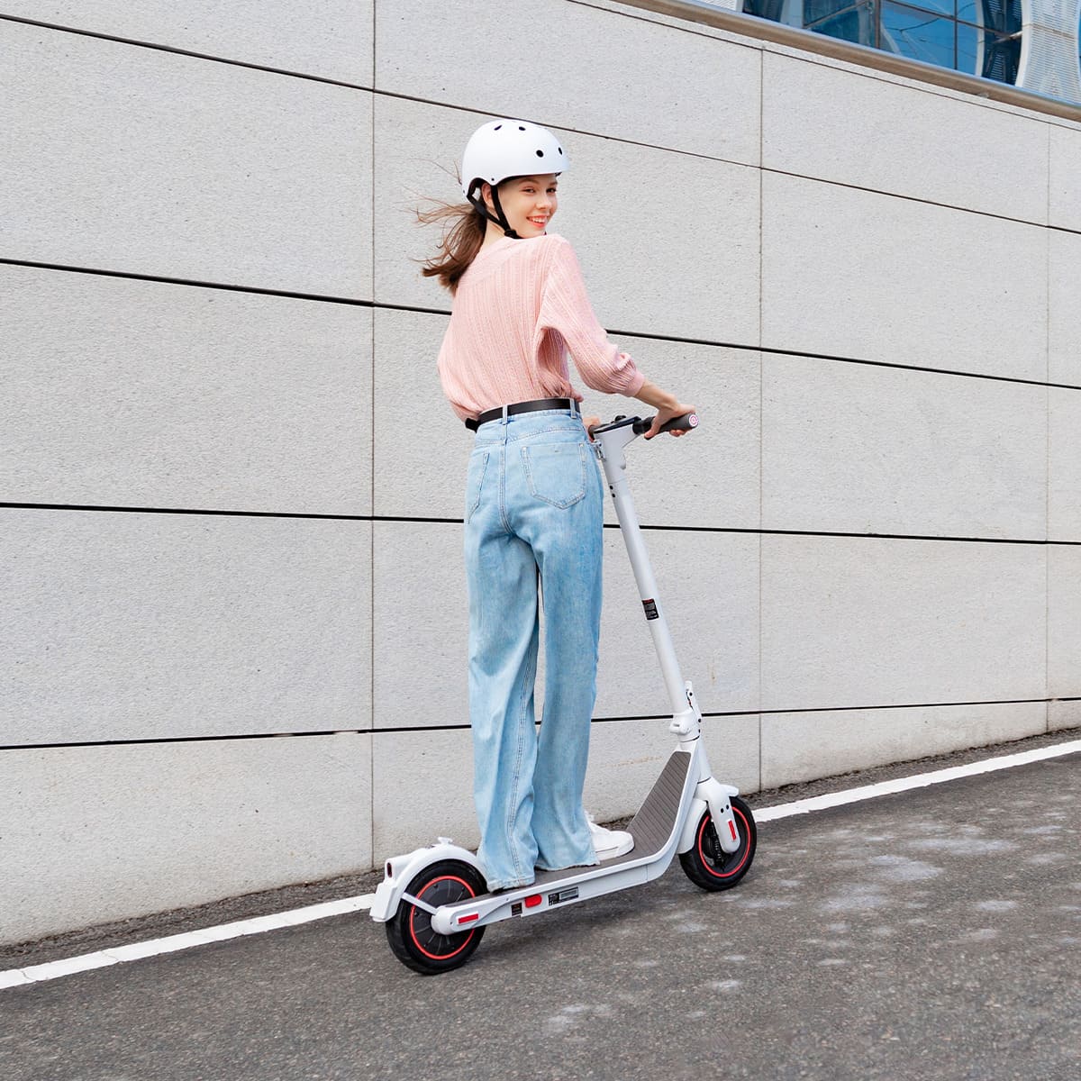 Person riding a scooter with a helmet on a city street.