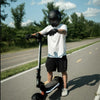 Person riding a scooter on a road with trees in the background