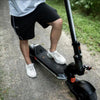 Person riding in Apollo Phantom 2 scooter on a paved path with grass on either side.