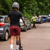 Person on an electric scooter with a traffic officer in a parking lot.