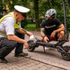 Person with Teverun Fighter 11 electric scooter being checked by a traffic officer on a city street.