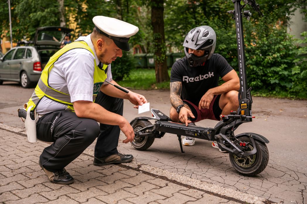 Person with Teverun Fighter 11 electric scooter being checked by a traffic officer on a city street.