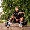 Man sitting on a Teverun Fighter 11 electric scooter in a park