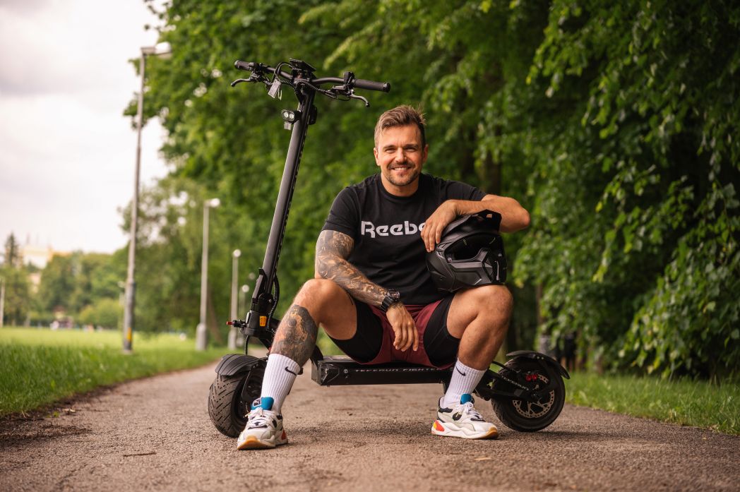 Man sitting on a Teverun Fighter 11 electric scooter in a park