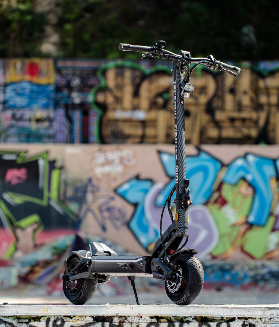 Black Teverun fighter Mini  electric scooter on a ledge with graffiti-covered wall in the background