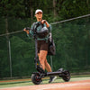 Person riding a fighter mini electric scooter on a track with a forest background