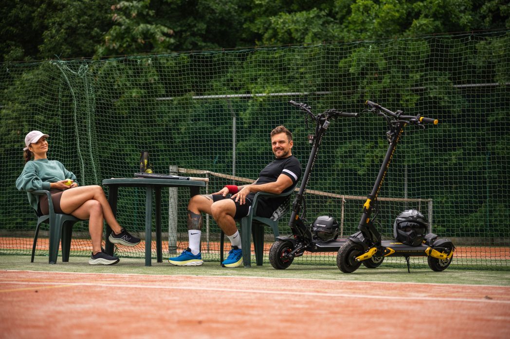 Two people sitting on a tennis court with Teverun fighter Mini electric scooters.