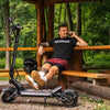 Man sitting on a wooden bench with a teverun fighter mini electric scooter in a forest setting