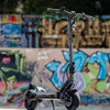 Black electric scooter on a ledge with graffiti-covered wall in the background