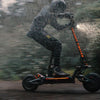 Person riding a Teverun Fighter Supreme Ultra electric scooter in the rain with a blurred background