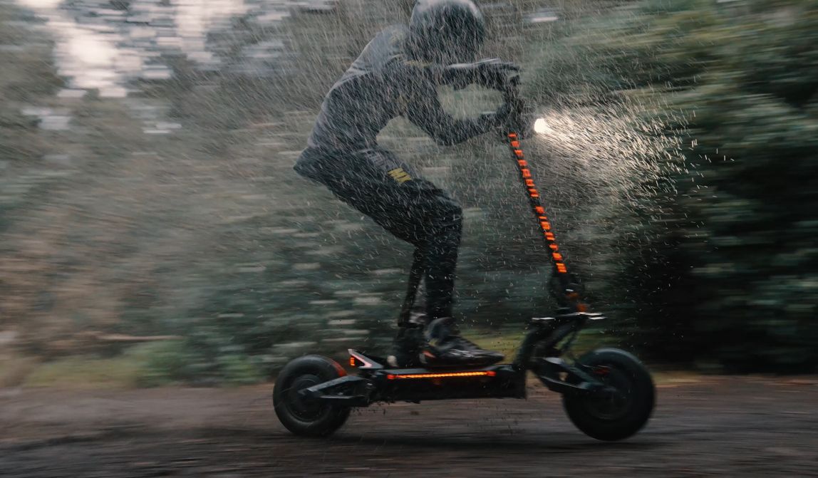 Person riding a Teverun Fighter Supreme Ultra electric scooter in the rain with a blurred background