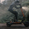 Person riding aTeverun Fughter Supreme Ultra electric scooter in the rain with a blurred background