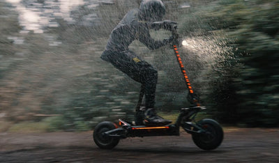 Person riding aTeverun Fughter Supreme Ultra electric scooter in the rain with a blurred background