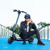 Man sits on the deck of his Punk Rider Pro electric scooter