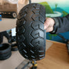 Person holding a black tire with tread pattern in an indoor setting