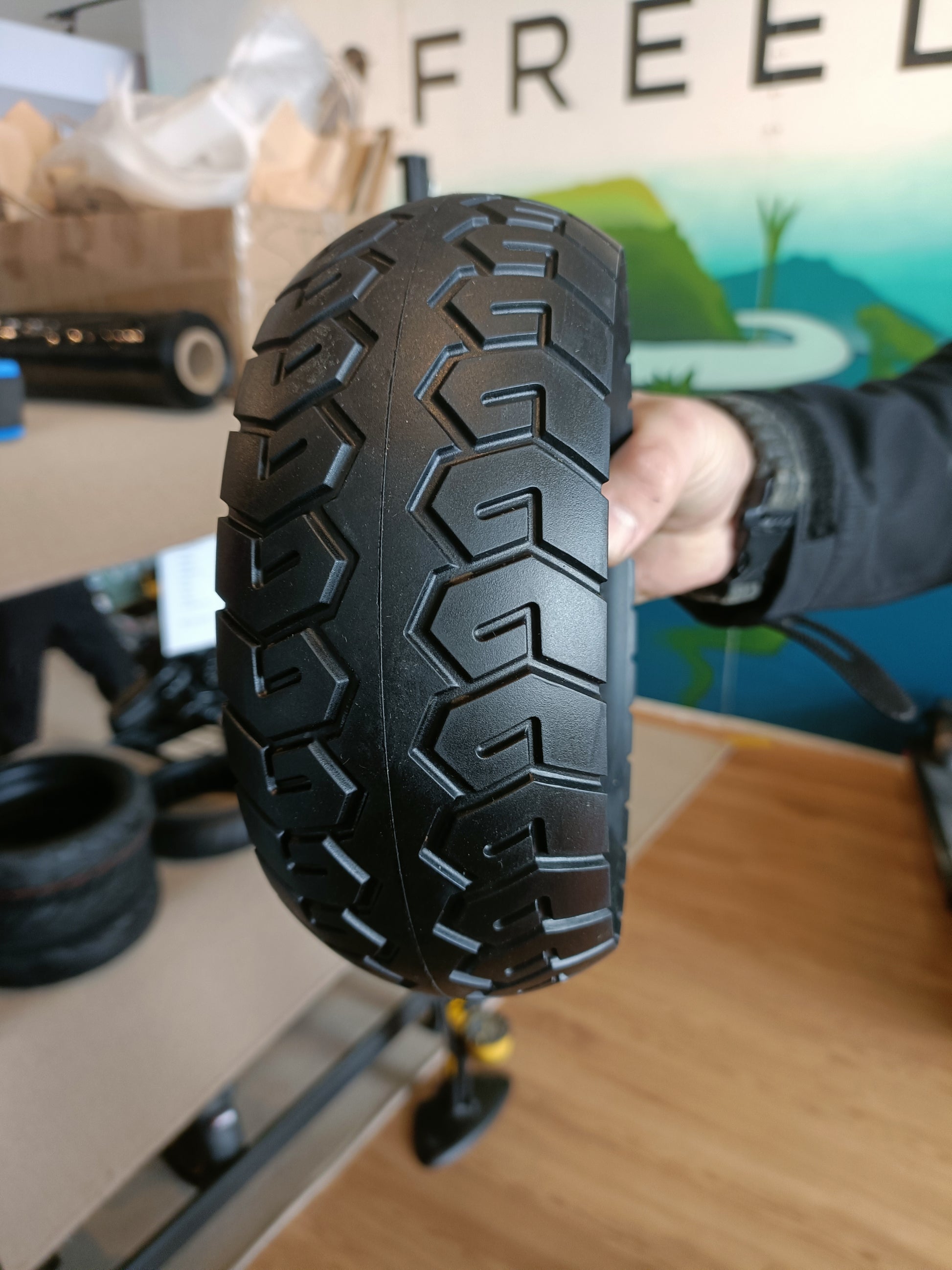 Person holding a black tire with tread pattern in an indoor setting